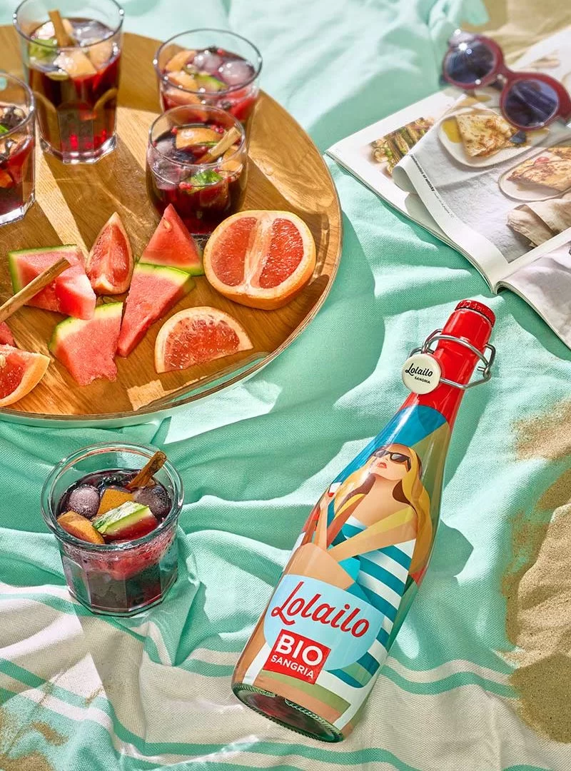 Sangria bio Lolailo en bouteille avec fruits et glaçons, parfaite pour un pique-nique en plein air.