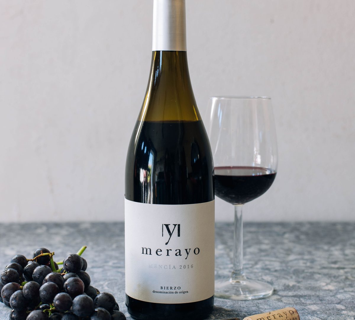 Bouteille de Bierzo Mencia 2016, accompagnée d’un verre de vin et de raisins, parfaite pour les amateurs de vin espagnol rouge.