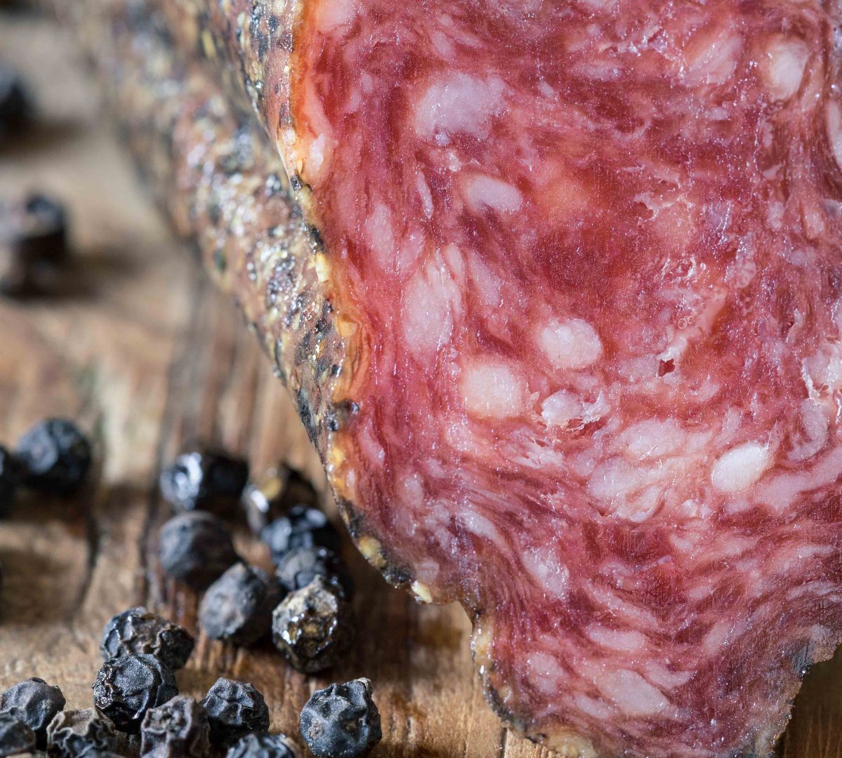 Gros plan sur une longanisse poivrée artisanale catalane avec grains de poivre noir.