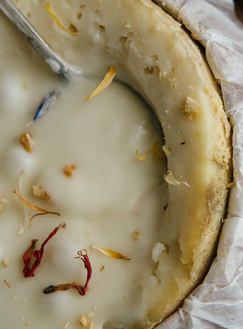 Vue rapprochée de la Torta del Casar, fromage espagnol crémeux de Cáceres, décoré de pétales de fleurs et d'arômes naturels.