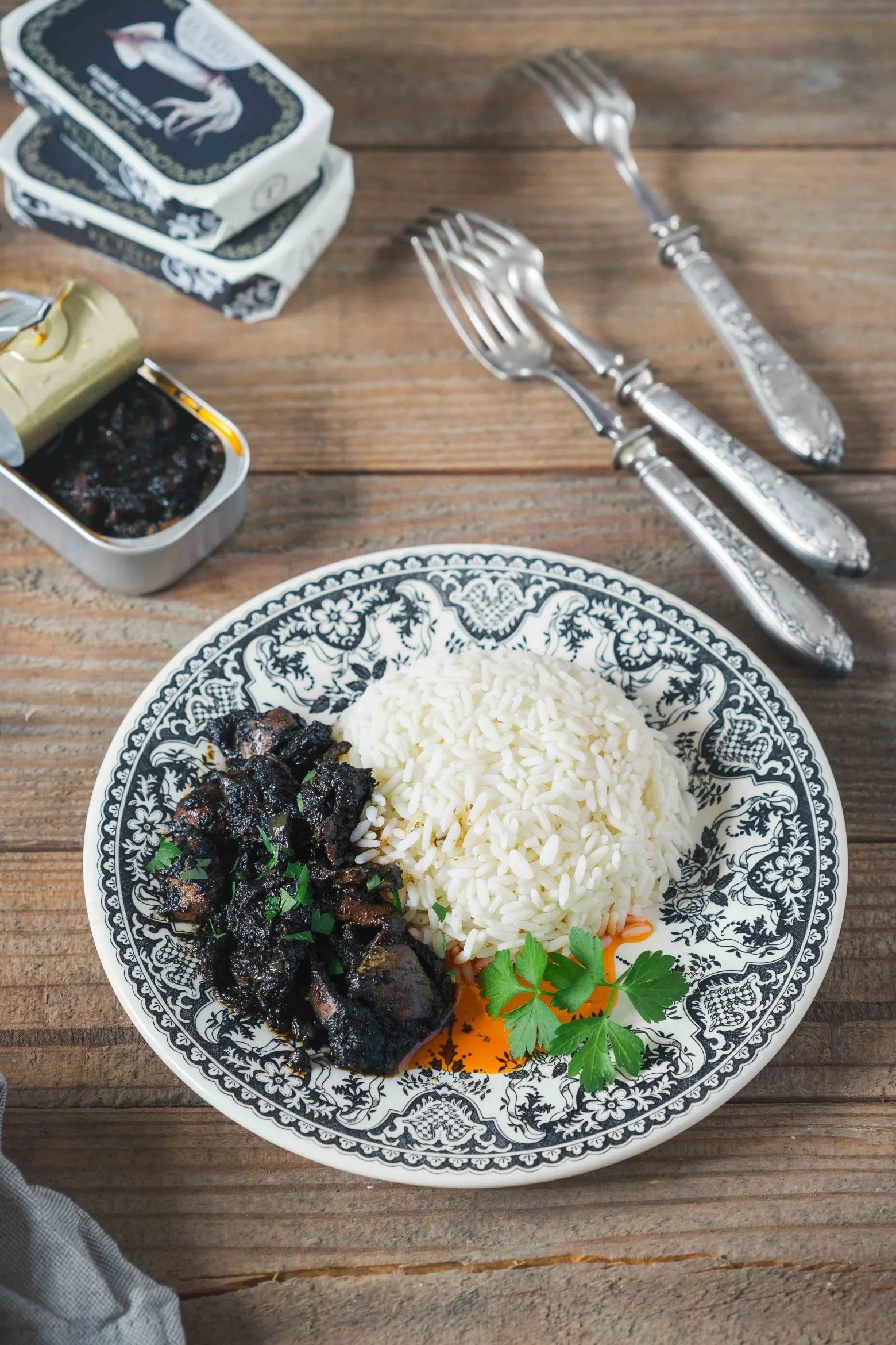 Plat de morceaux de calamar Calle El Tato dans une sauce à l’encre noire, accompagné de riz.