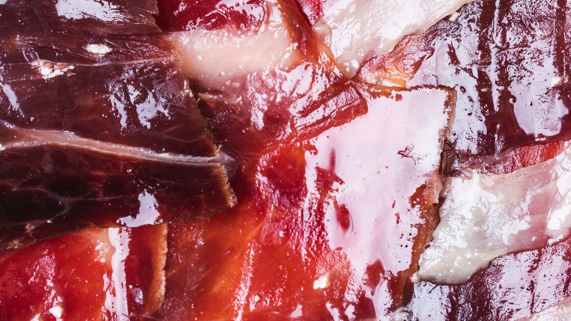 Gros plan sur des tranches de jambon ibérique Bellota, à la texture marbrée et savoureuse.