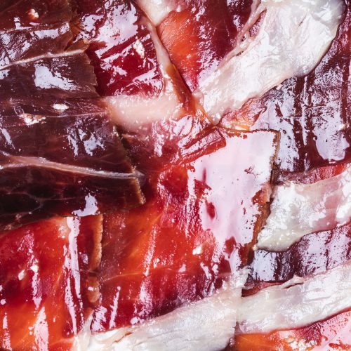Gros plan sur des tranches de jambon ibérique Bellota, à la texture marbrée et savoureuse.