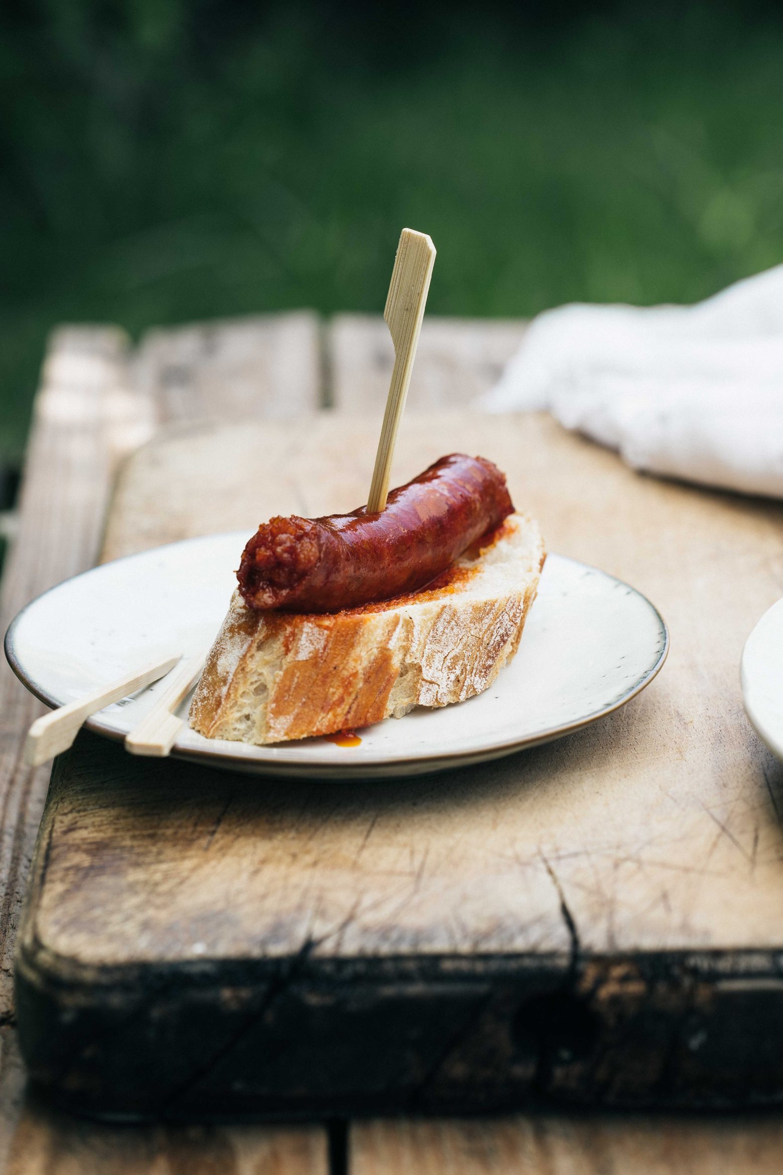 Txistorra basque servie sur une tranche de pain rustique, idéale pour les barbecues ou planchas.