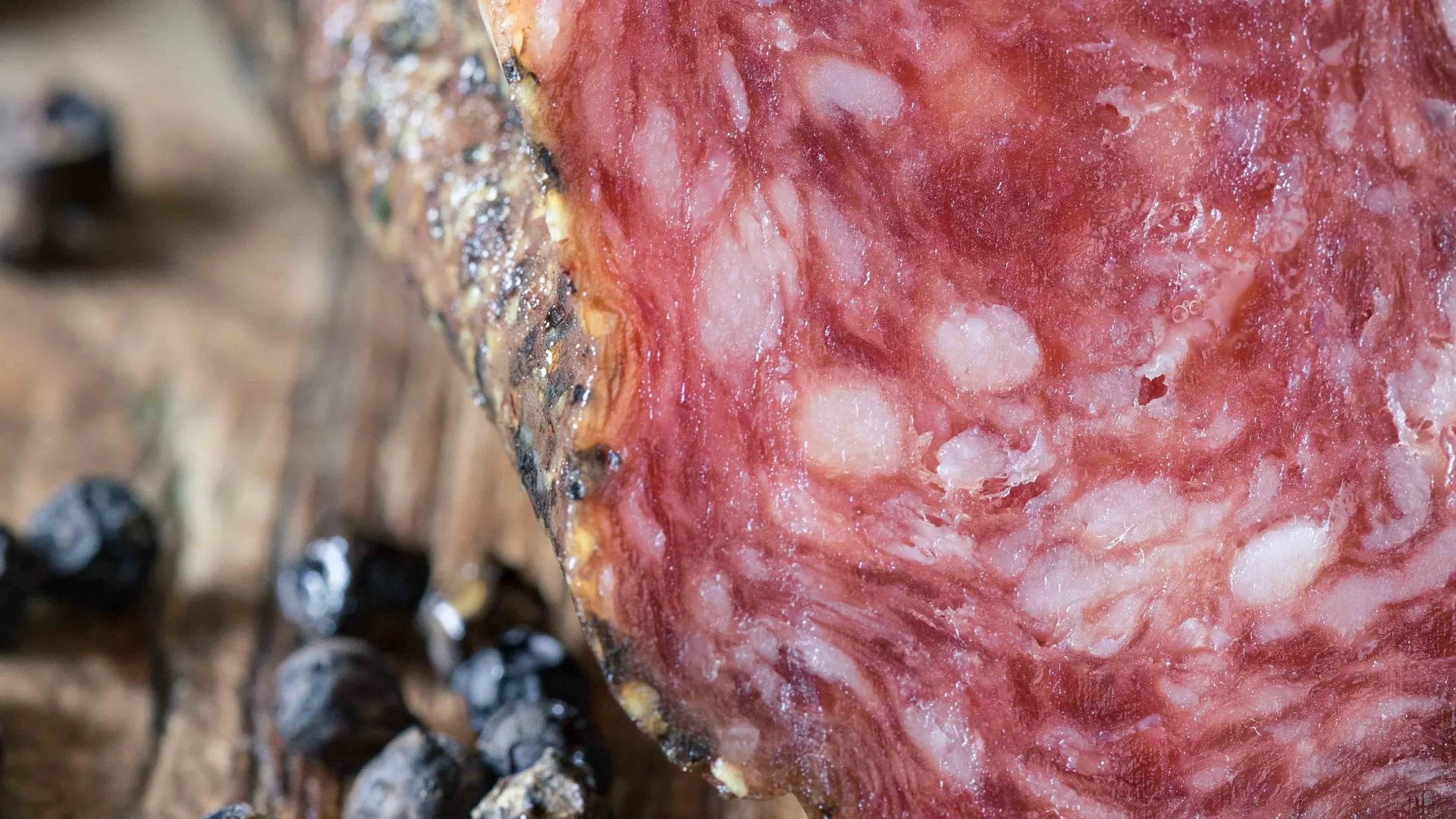 Gros plan sur un saucisson catalan artisanal avec grains de poivre, un produit de charcuterie haut de gamme.