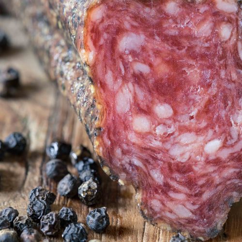 Gros plan sur un saucisson catalan artisanal avec grains de poivre, un produit de charcuterie haut de gamme.