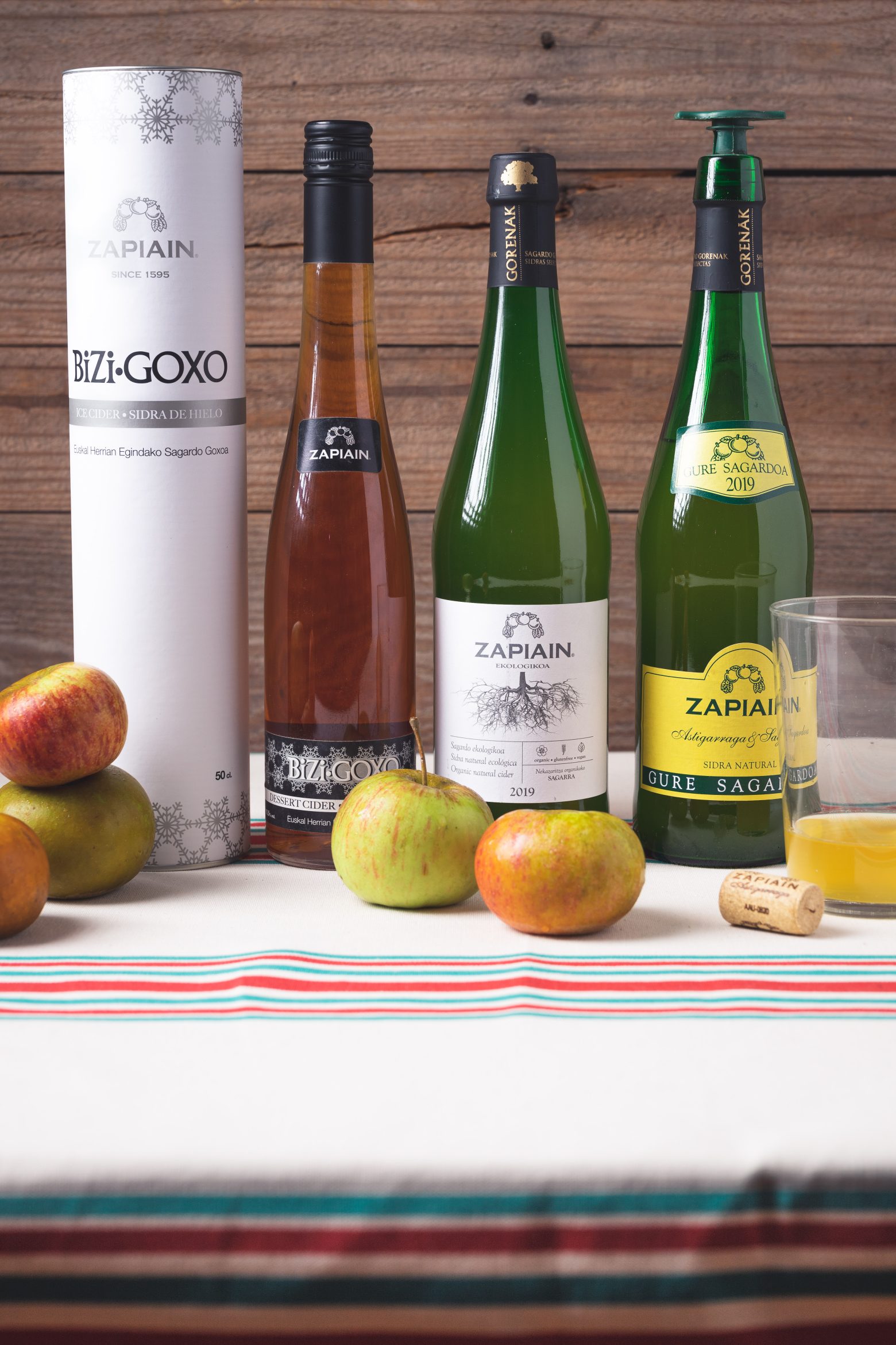 Bouteilles de cidre basque Zapiain, y compris une version bio et le cidre des neiges, entourées de pommes.