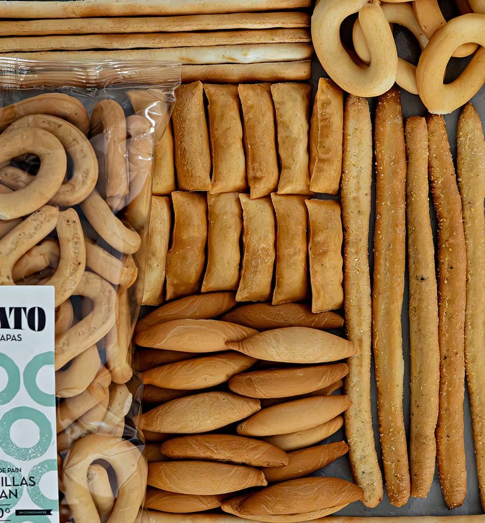 Assortiment de spécialités espagnoles haut de gamme : gressins, picos, et rosquillas en présentation soignée.