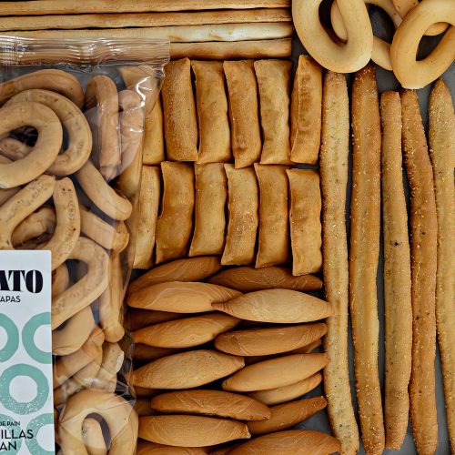 Assortiment de spécialités espagnoles haut de gamme : gressins, picos, et rosquillas en présentation soignée.