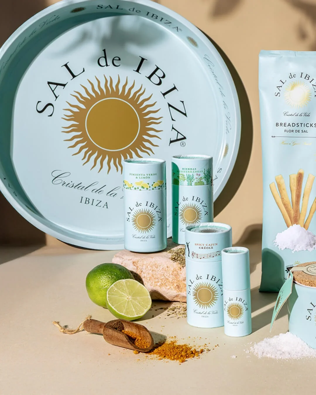 Produits de la gamme fleur de sel Sal de Ibiza : tubes de sel aromatisé, pot en céramique, sachet de gressins artisanaux et plateau aux couleurs turquoise emblématiques, accompagnés de citron vert et d’épices.