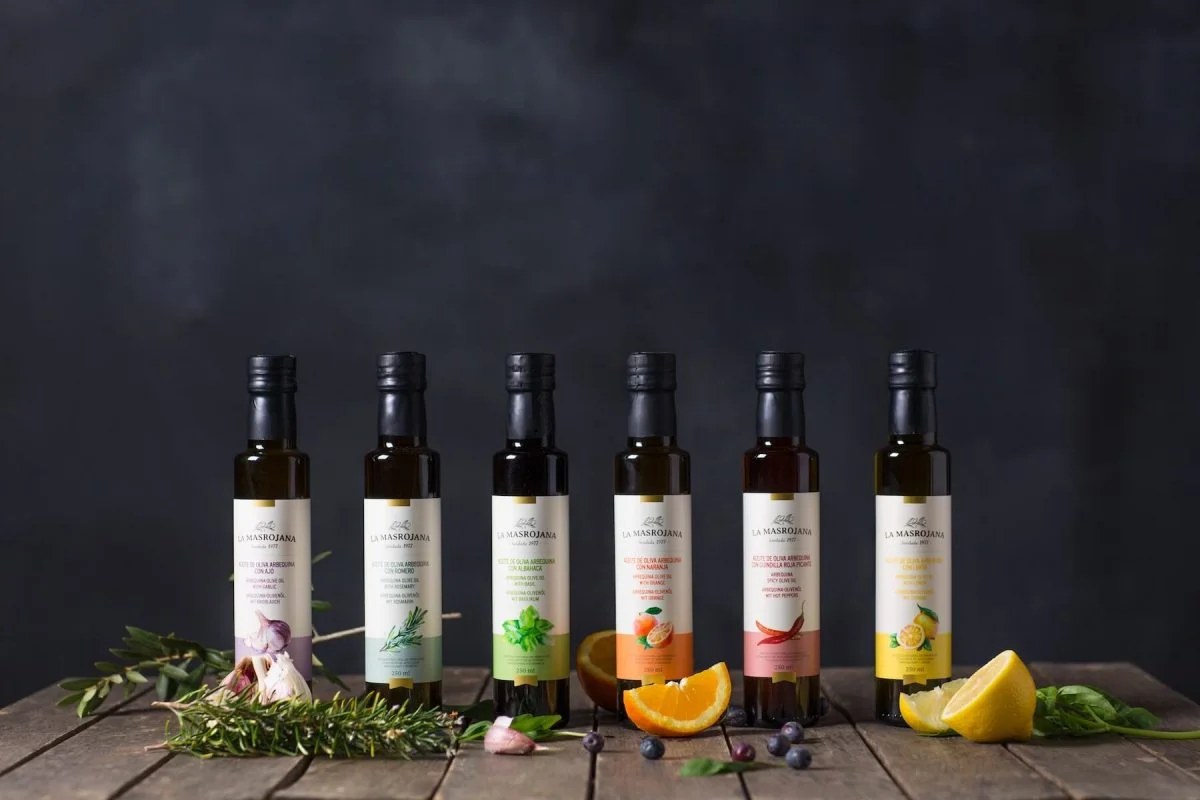 Bouteilles d’huile d’olive infusée La Masrojana alignées sur une table en bois