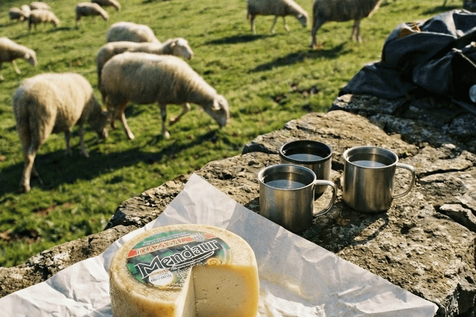 Fromage Idiazabal entier et tranché, posé sur une planche rustique
