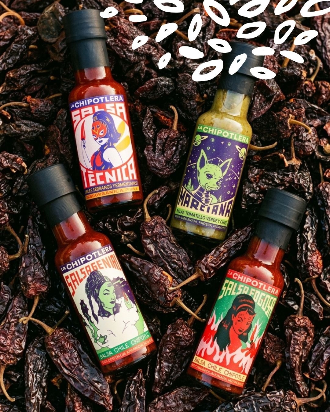 Bouteilles de sauces bio La Chipotlera, dont Marciana salsa verde, posées sur un lit de piments séchés
