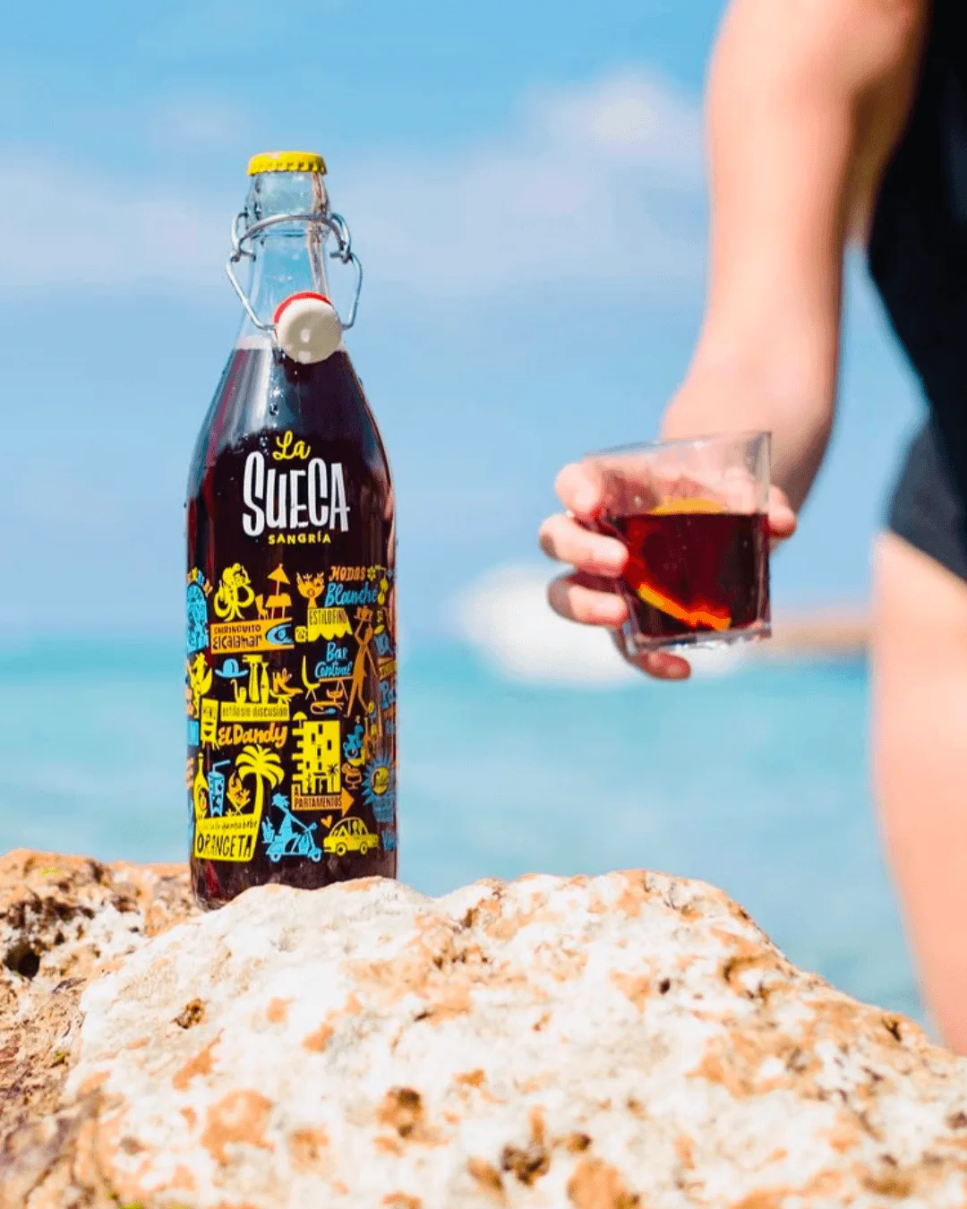 Bouteille de sangria La Sueca et verre servi face à la mer Méditerranée.