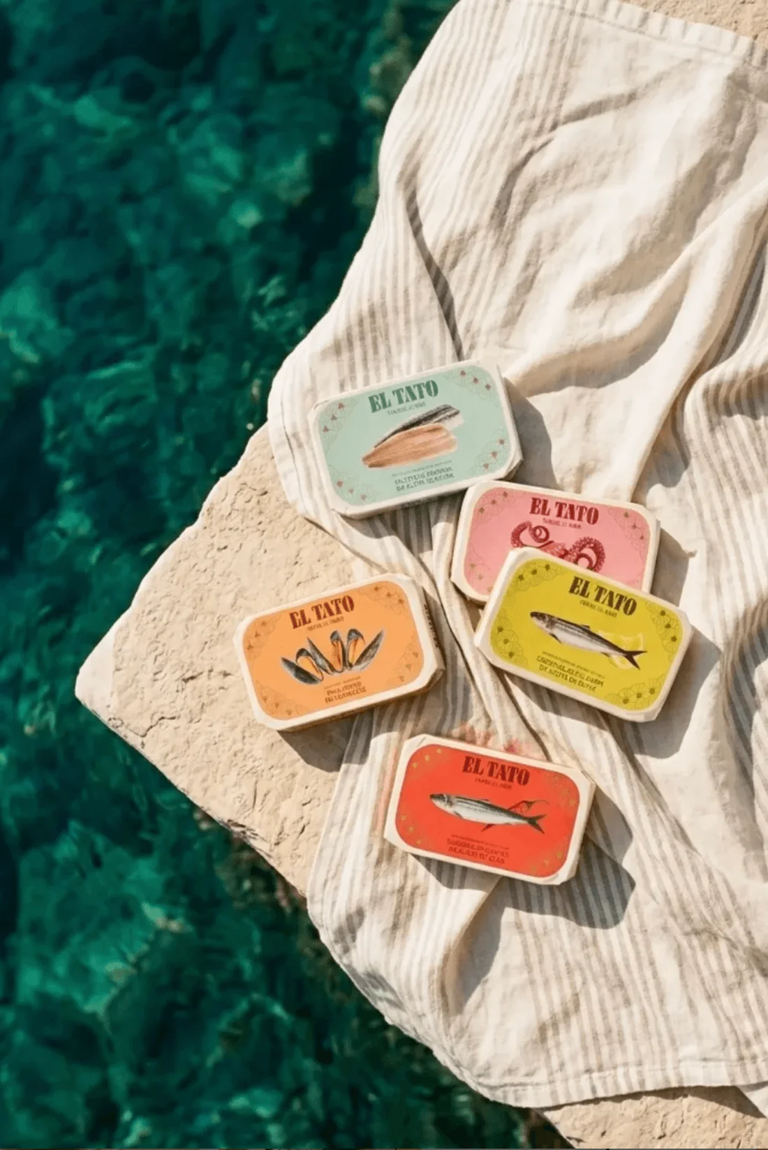 Sélection de conserves artisanales El Tato présentées au bord de l'eau, inspirées des traditions maritimes espagnoles.