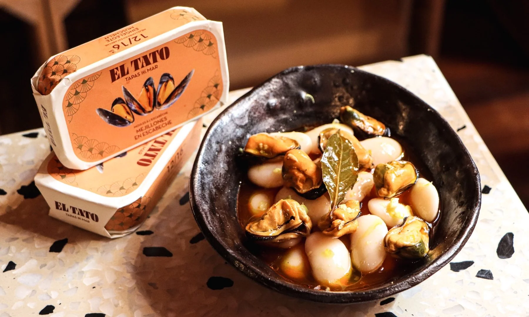 Moules en escabèche El Tato servies avec des haricots blancs dans une recette inspirée de la gastronomie espagnole.