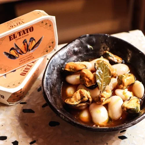 Moules en escabèche El Tato servies avec des haricots blancs dans une recette inspirée de la gastronomie espagnole.
