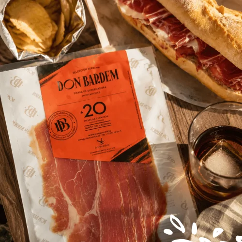 Serrano Gran Reserva Don Bardem prétranché, affiné plus de 20 mois à Montánchez, présenté avec un sandwich gourmet.